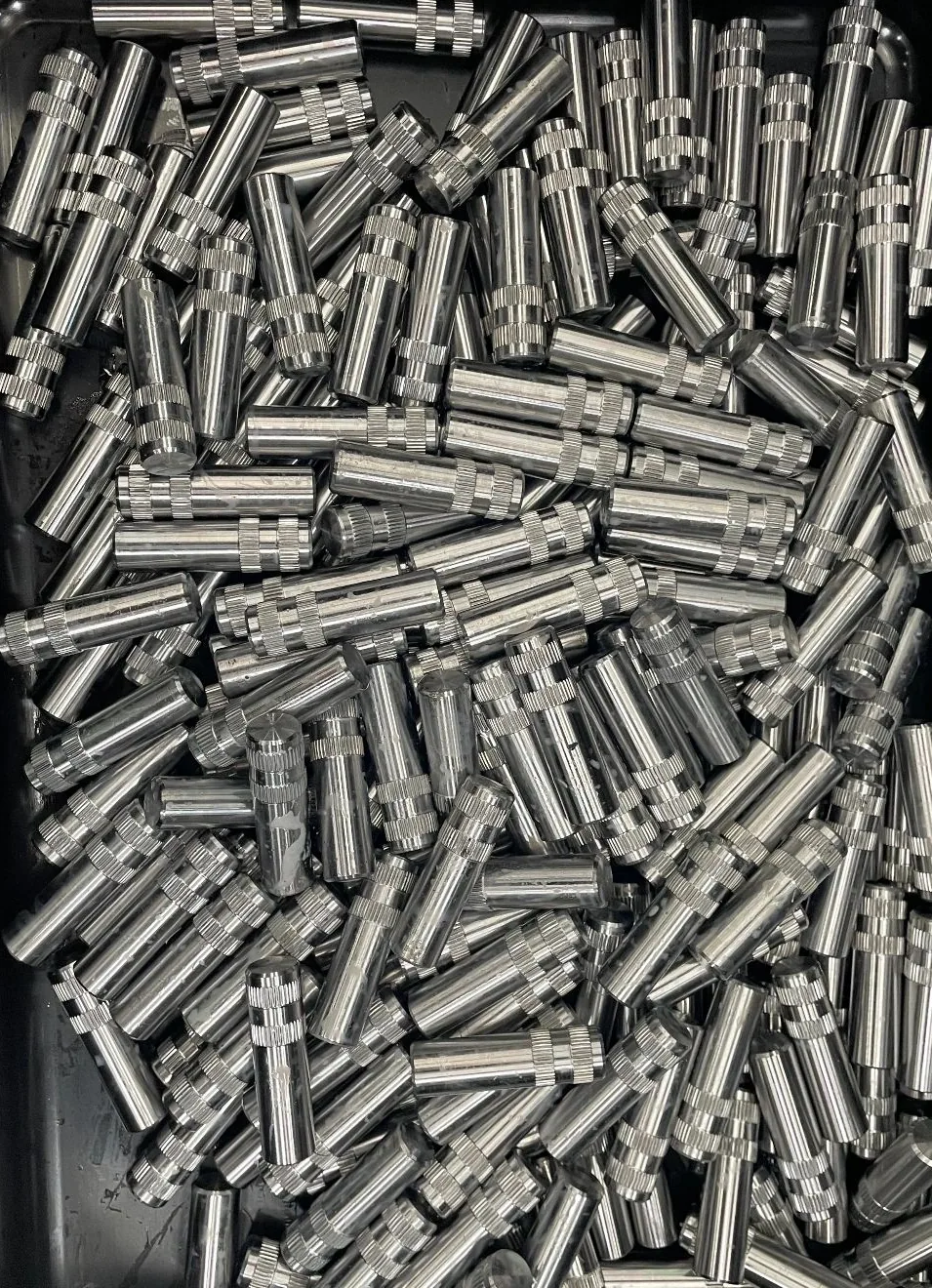 Bin of knurled stainless machined pins, production volume