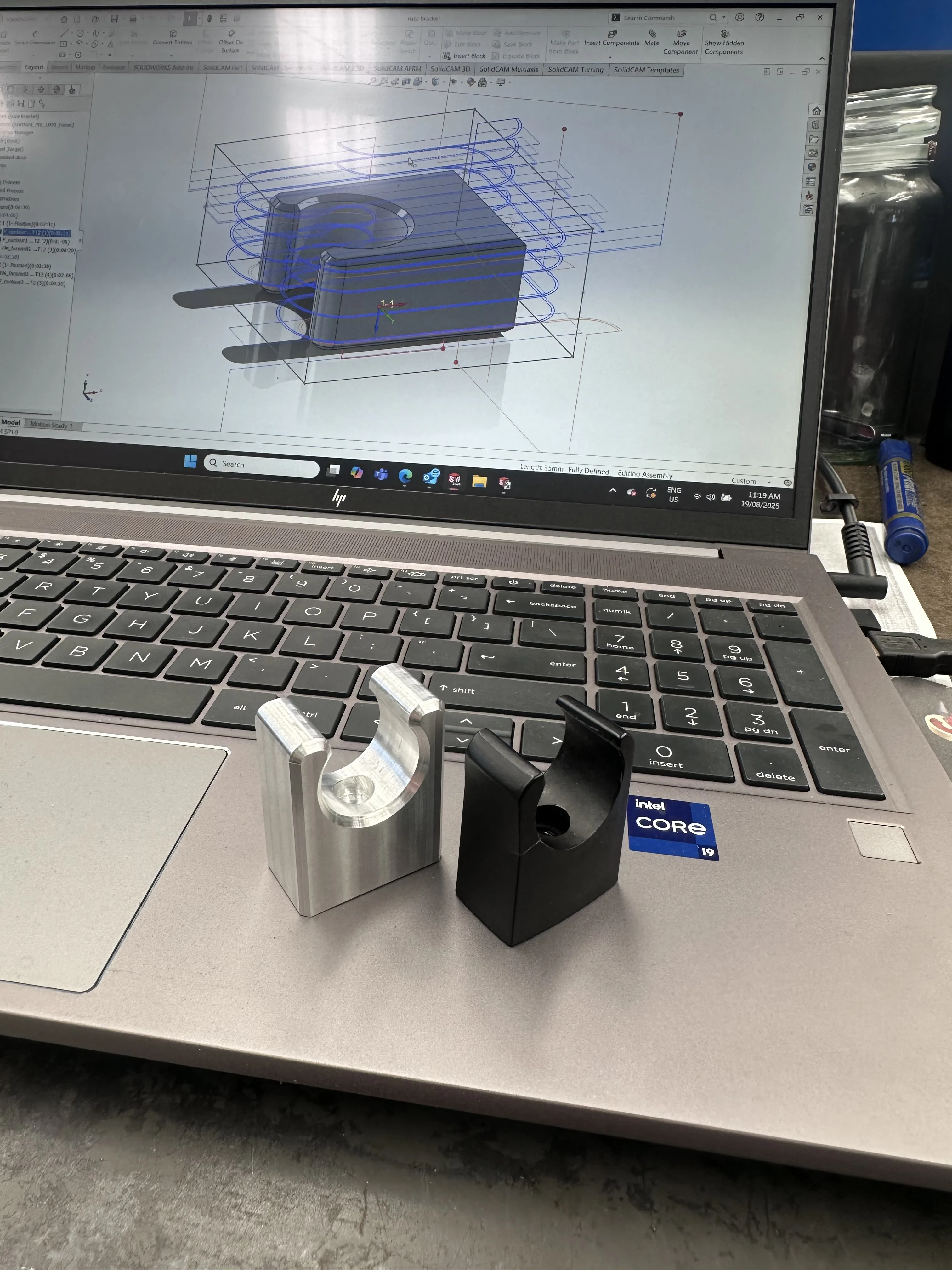 SolidCAM toolpath on screen with raw stock and finished aluminium bracket — design to part, Padco Engineering