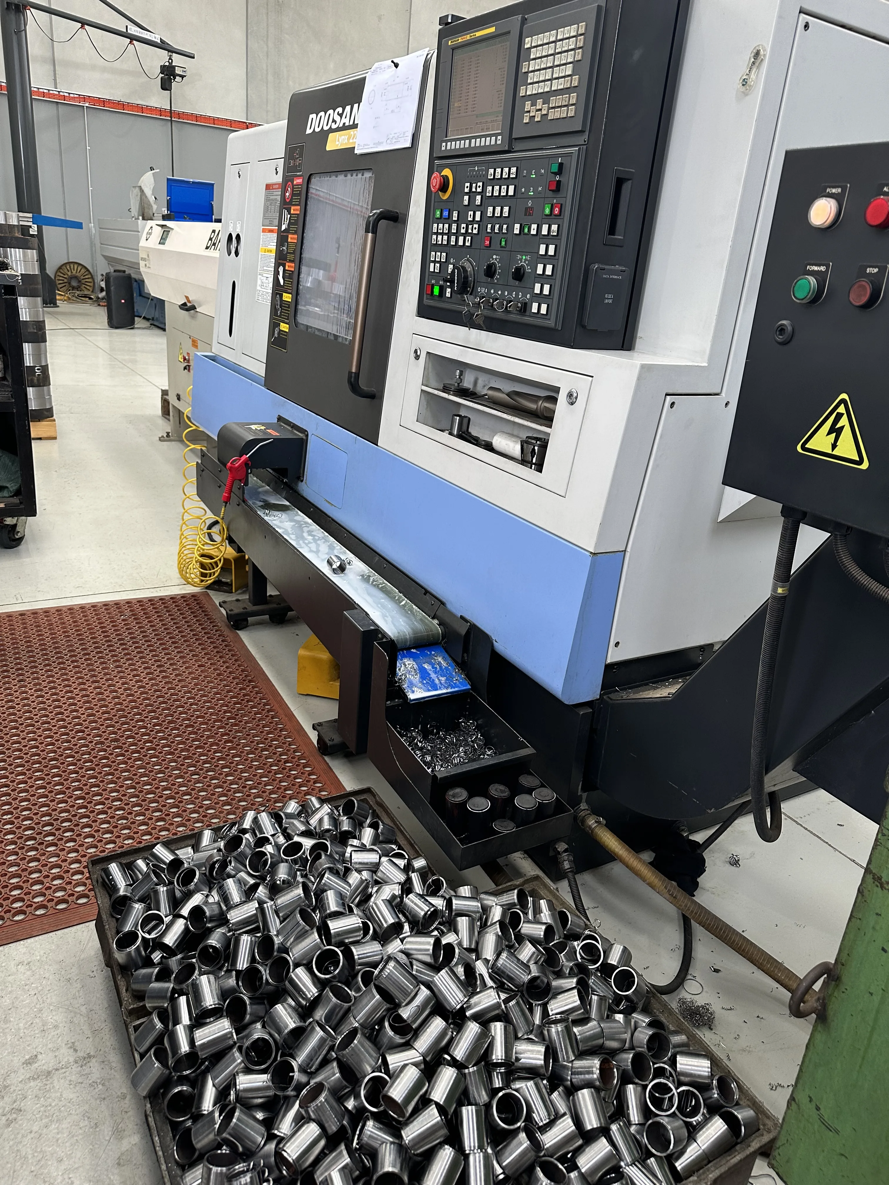 Doosan Lynx 220 CNC turning centre with tray of freshly turned steel bushings, Padco Engineering