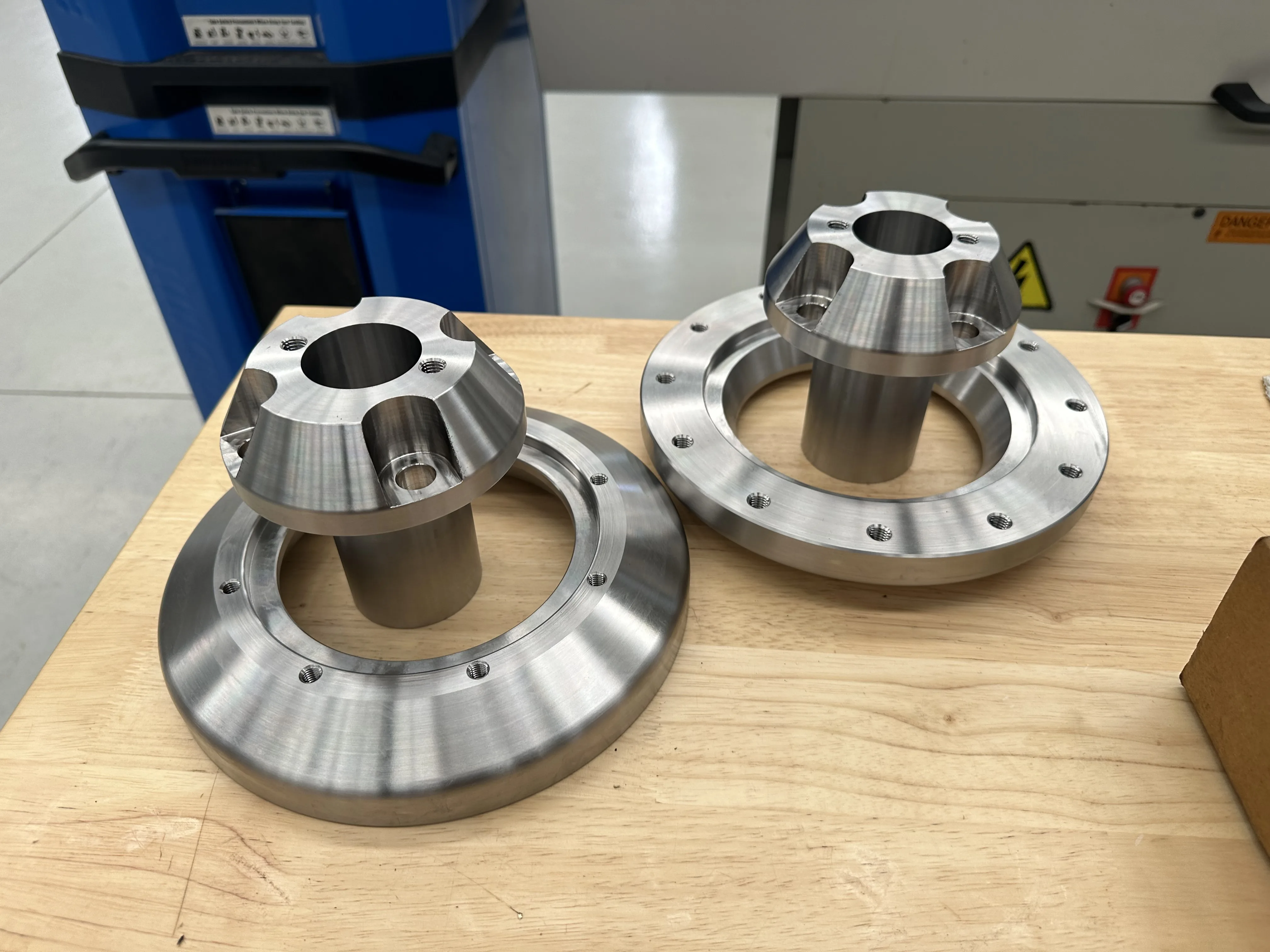 Finished stainless hub-and-flange assemblies — turned conical hubs on flanged bases, Padco Engineering